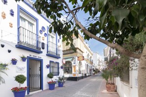 Calle con edificios, incluyendo un hotel llamado "Casa Azul" con fachada azul y blanca, plantas en macetas y cielo despejado.