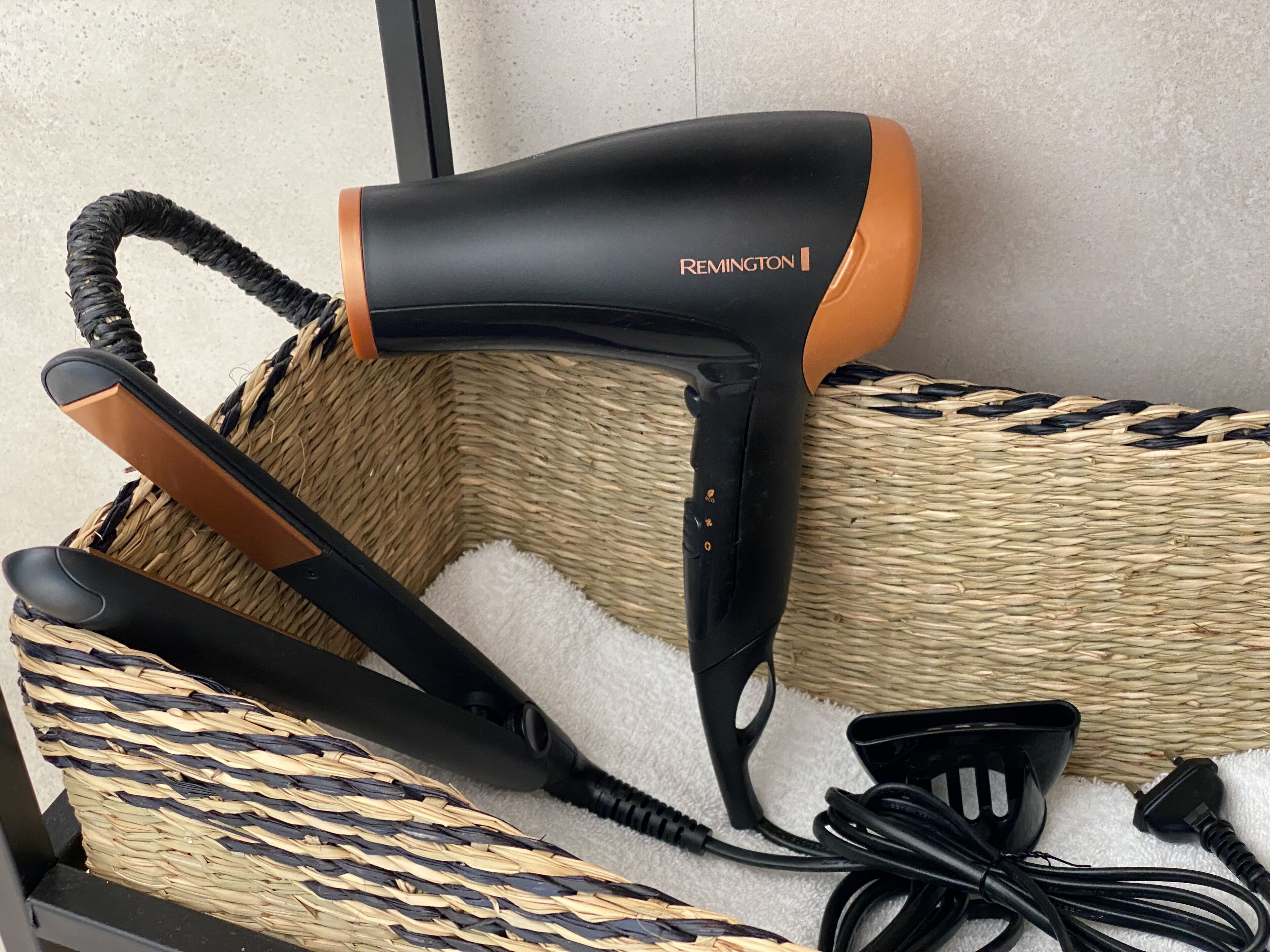 Un secador de pelo y sus accesorios en una cesta tejida.