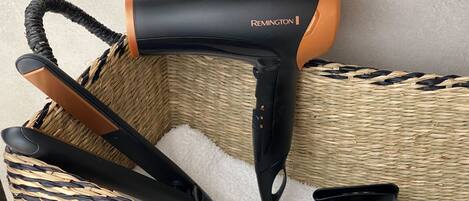 A hair dryer and its accessories in a woven basket.