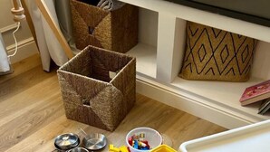 Espaço infantil com brinquedos, caixas organizadoras e uma mesa.