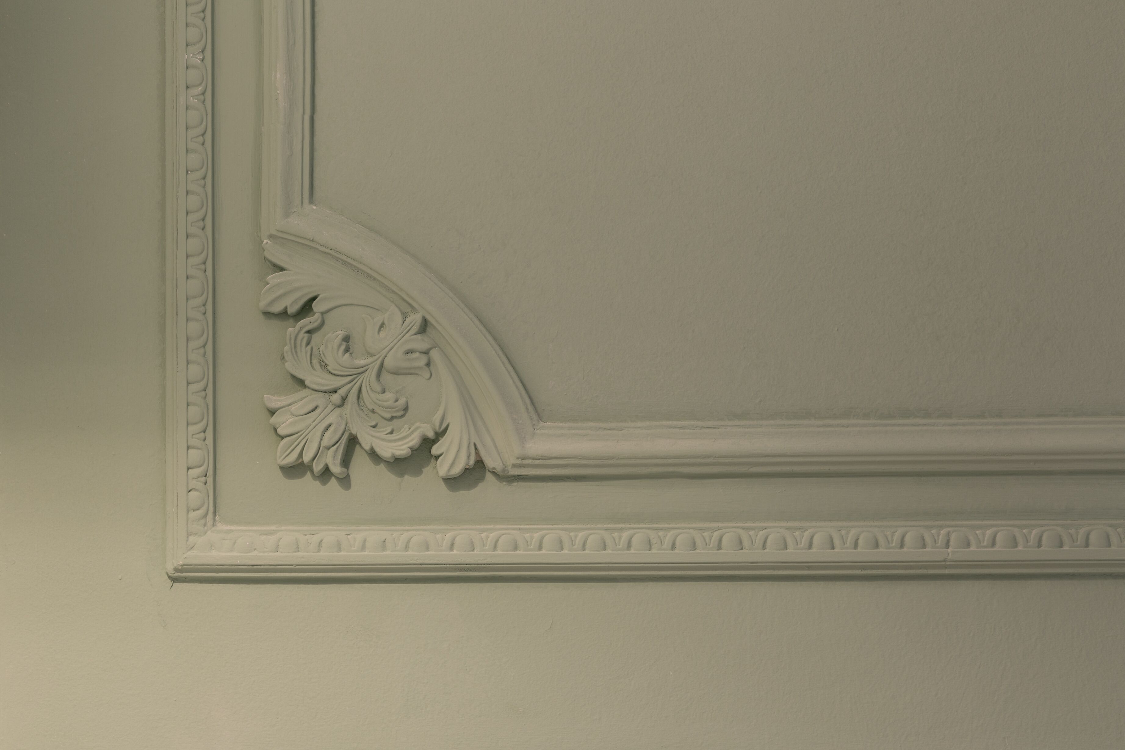 A wall with a decorative molding and a floral design.