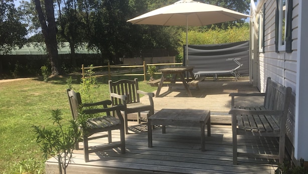 A wooden deck with outdoor furniture, including chairs and a table, and a large umbrella providing shade. - Nature lovers by the sea (Bormes-les-Mimosas)