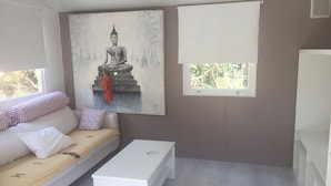 A room with a bed, a white bench, a painting of a Buddha statue, and a window with a view of trees. - Nature lovers by the sea (Bormes-les-Mimosas)