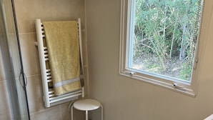 A bathroom with a shower, a small stool, a window with a view of greenery, and a bathtub. - Nature lovers by the sea (Bormes-les-Mimosas)