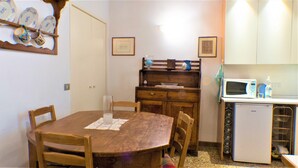 Ein Essbereich mit einem Holztisch, Stühlen, einem kleinen Kühlschrank und einer Mikrowelle.