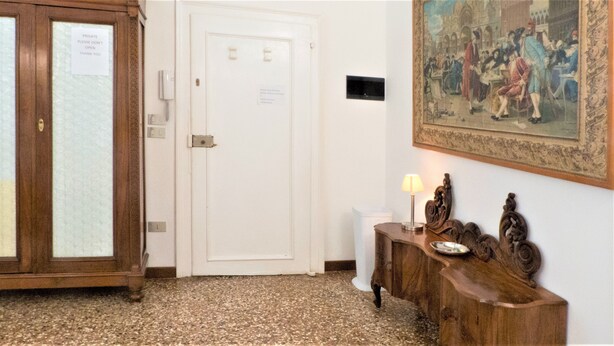Ein Flur mit einer weißen Tür, einem Holzschrank mit einer Lampe und einem gerahmten Gemälde an der Wand.