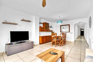 Una sala de estar moderna con una televisión de pantalla plana, una mesa de comedor de madera y sillas.