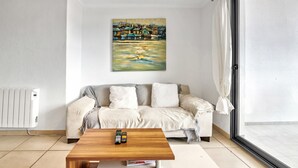 Un salon avec un canapé, une table basse et un tableau accroché au mur.