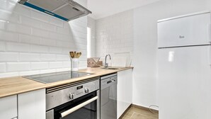 Une cuisine moderne avec des carreaux de céramique blancs disposés en motif métro, des appareils électroménagers en acier inoxydable, un plan de travail en bois et un lave-vaisselle encastré.