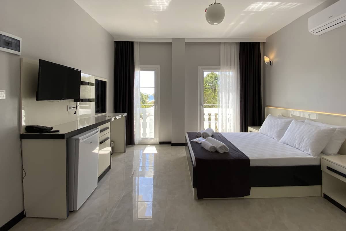 A hotel room with a bed, bedside table, desk, and TV.
