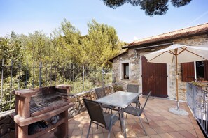 A stone building with a barbecue area, outdoor table and chairs, and a large umbrella.