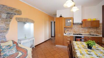 A kitchen with wooden cabinets, a tiled backsplash, and a dining table with a floral tablecloth.