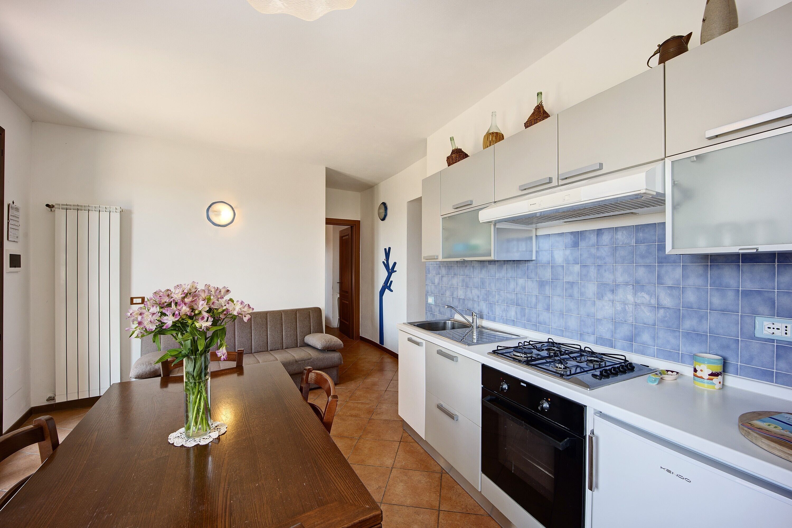 Een moderne keuken met witte kasten, een gasfornuis en een blauwe tegelachtergrond.