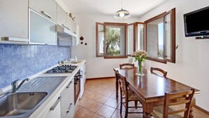 Una cocina con lavamanos, estufa y mesa de comedor con sillas.