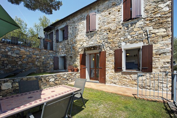 A stone building with a patio, outdoor seating, and a door leading to an interior space.
