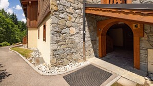 A stone building with a wooden balcony, a stone wall, and a paved entrance. - Apartment 'Morrillon 1100 Ski-in/Ski-out' with Mountain View, Balcony and Wi-Fi (Morillon)