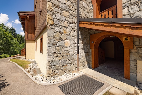 Un bâtiment en pierre doté d’un balcon en bois, d’un mur en pierre et d’une entrée pavée.