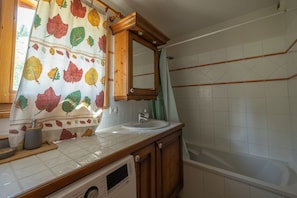 Une salle de bain avec un meuble-lavabo en bois, un évier, un miroir et une baignoire.