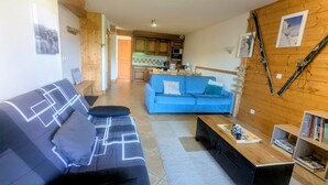 A living room with a blue sofa, a black sofa, a coffee table, and a bookshelf. - Apartment 'Morrillon 1100 Ski-in/Ski-out' with Mountain View, Balcony and Wi-Fi (Morillon)