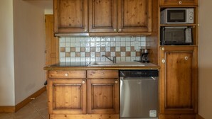 A kitchen with wooden cabinets, a dishwasher, a microwave, and a tiled backsplash. - Apartment 'Morrillon 1100 Ski-in/Ski-out' with Mountain View, Balcony and Wi-Fi (Morillon)