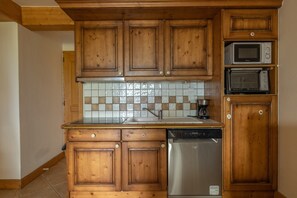 Une cuisine avec des meubles en bois, un lave-vaisselle, un four à micro-ondes et un dosseret carrelé.