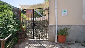 A gated entrance with a sign, a potted plant, and a stone wall.