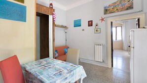 A room with a table, a chair, a radiator, and a door leading to another room.