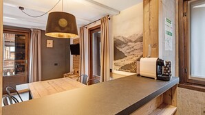 Eine moderne Küche mit einer Holz Arbeitsplatte, einer Kaffeemaschine und Blick auf Berge durch ein Fenster.