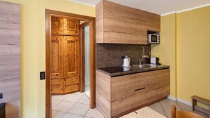 Une cuisine de taille réduite, dotée de meubles en bois, d’un four à micro-ondes et d’un évier.