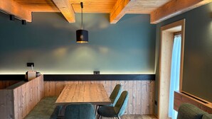 Ein gemütliches Zimmer mit Holzbalkendecke, einem Tisch mit Stühlen und einer Couch.