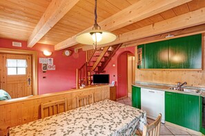 A wooden interior with a bed, a TV, a staircase, and a green kitchen area.