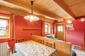 A wooden interior with a dining table, chairs, a bench, and a ceiling fan.