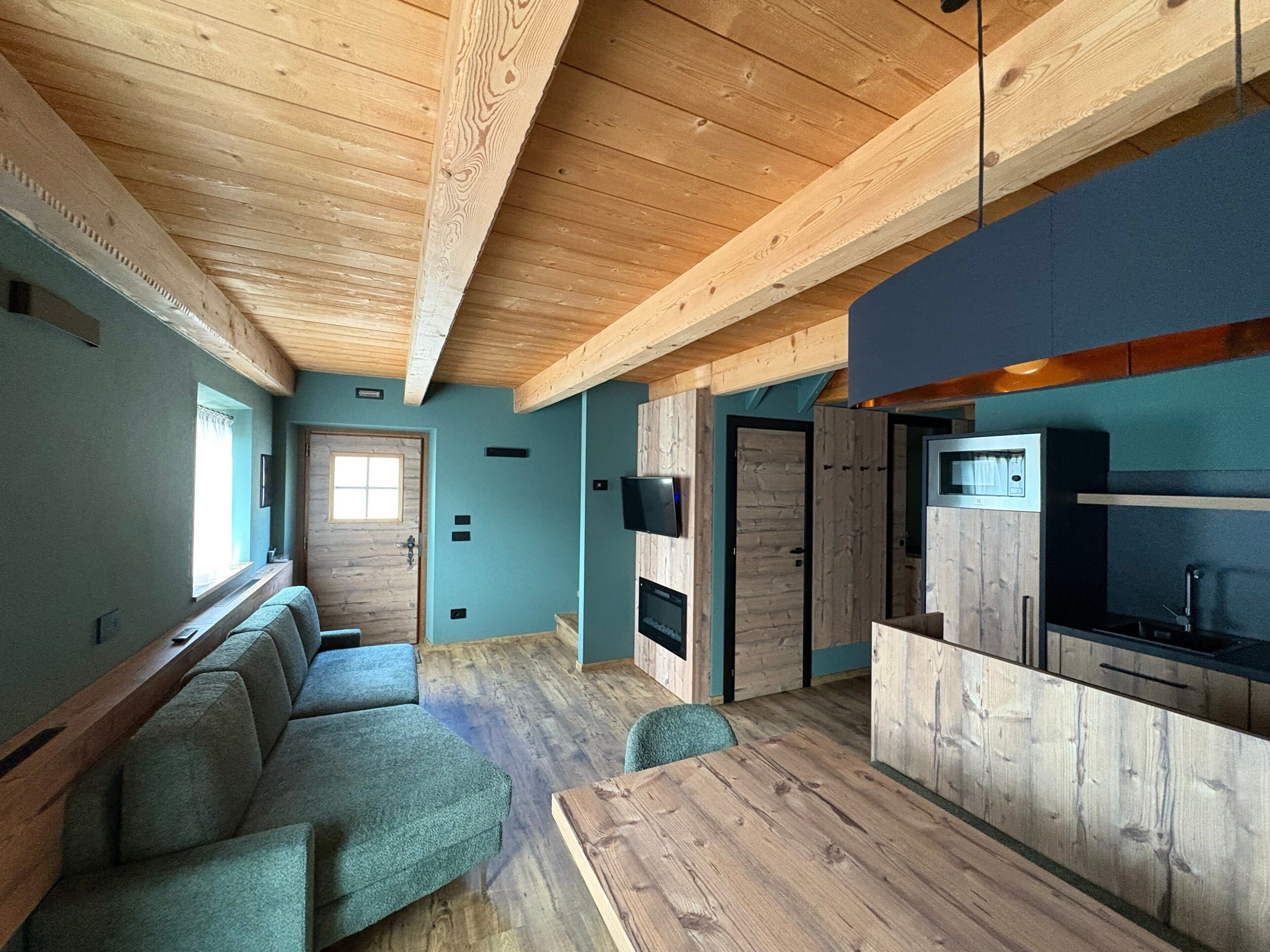 Un interior moderno con techo de madera, una cocina integrada y una zona de estar con sofá y mesa.