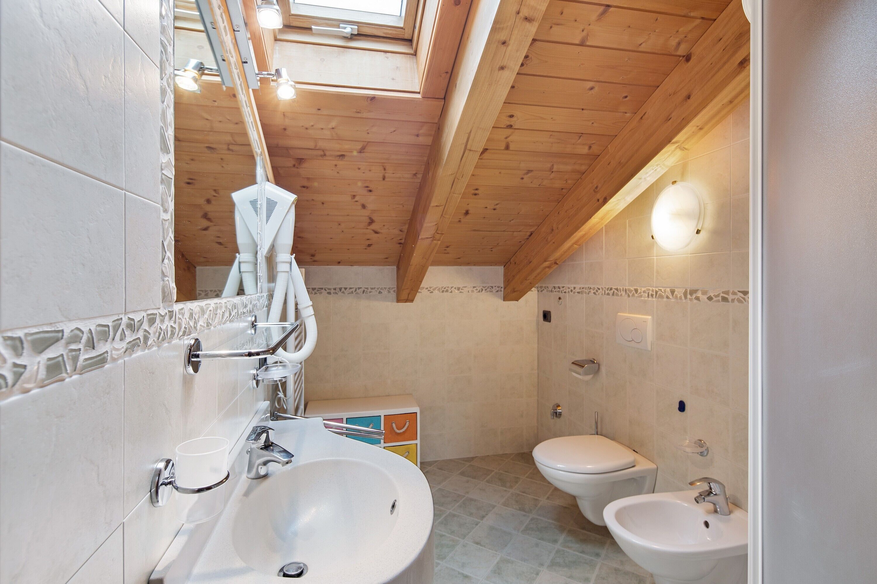 Une salle de bain avec un puits de lumière, deux lavabos et des toilettes.