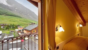 Ein Zimmer mit Bergblick, ein Balkon mit Geländer und ein Bett mit Kopfteil.
