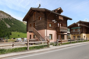 Ein Chalet im Holzbau mit Balkon, Treppe und einem Schild mit der Aufschrift 'Chalet Kiara'.