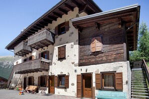 Un chalé tradicional con balcones de madera, paredes de piedra y una escalera que conduce a los pisos superiores.