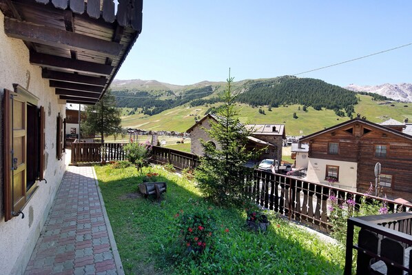A traditional wooden building with a balcony overlooking a rural landscape with mountains.
