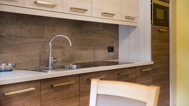 A modern kitchen with a stainless steel sink, wooden cabinets, and a built-in oven. - Apartment Baita Belvedere - Teola with Mountain View, Balcony and Wi-Fi (Livigno)