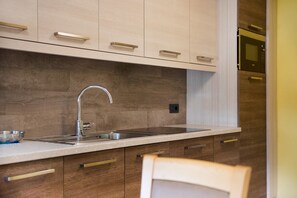 Une cuisine moderne dotée d’un évier en acier inoxydable, de meubles en bois et d’un four encastré.
