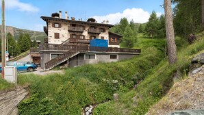 A multi-story building with balconies, a staircase, and a sign that reads 'BATTABEAU.' - Apartment Baita Belvedere - Teola with Mountain View, Balcony and Wi-Fi (Livigno)