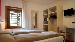 A bedroom with two beds, a window with blinds, a desk with a chair, and a TV mounted on the wall. - Apartment Baita Belvedere - Teola with Mountain View, Balcony and Wi-Fi (Livigno)