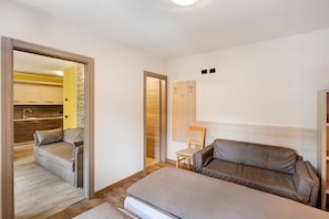 Une chambre à coucher comprenant un canapé, un fauteuil, un lit et une armoire en bois.