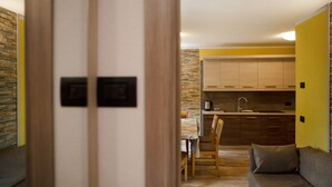 A modern kitchen with wooden cabinets, a dining table with chairs, and a sofa in a living area. - Apartment Baita Belvedere - Teola with Mountain View, Balcony and Wi-Fi (Livigno)