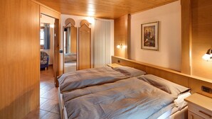Une chambre à coucher avec un lit, une tête de lit en bois, des tables de chevet, une lampe fixée au mur et un tableau.