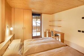 Un dormitorio con dos camas, muebles de madera, un escritorio y una ventana con vistas.
