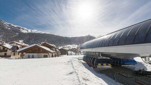 Un paysage enneigé avec une gare, des bâtiments en bois et des montagnes en arrière-plan.