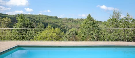 A swimming pool with a view of a forested hillside.
