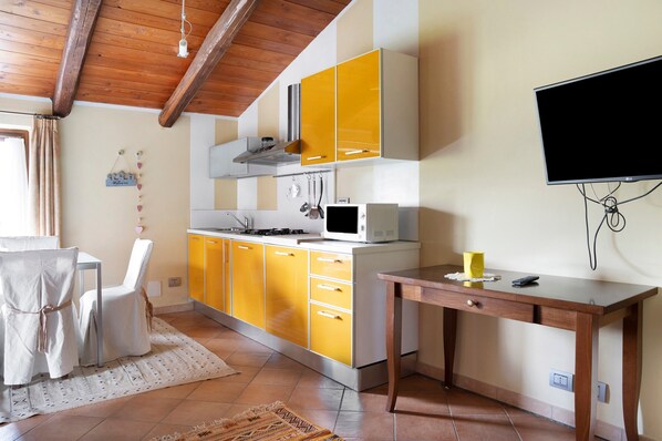 Una cocina funcional con armarios amarillos, un microondas y una mesa de madera.
