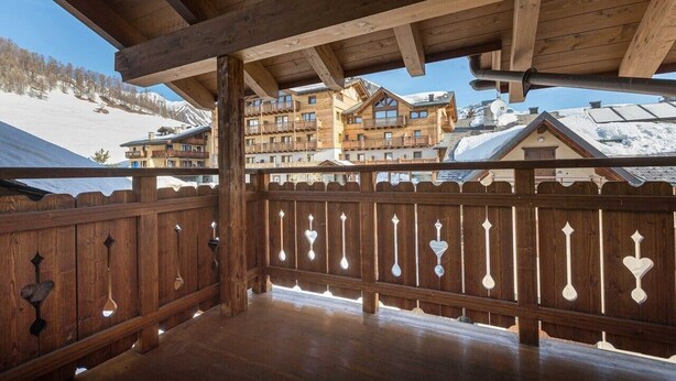 A wooden balcony with a view of snow-covered buildings and a clear sky. - Apartment 'Miky House Valandrea' with Mountain View, Balconies and Wi-Fi (Livigno)